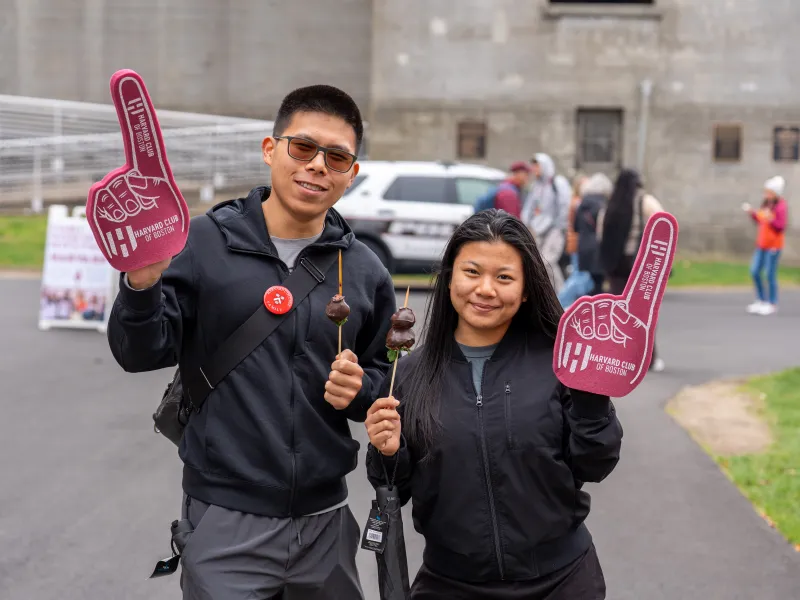 Two young people hold up red Harvard foam fingers.