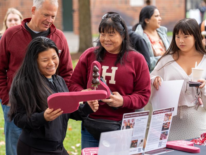 A student and her mom smile while picking up a Harvard foam finger at the merchandise table.
