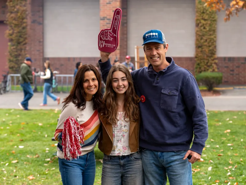 A female student smiles for a picture with her parents.