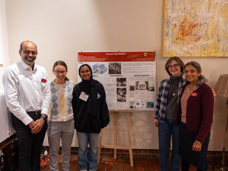 The Measure Mather team smile for a photo together next to a posterboard explaining their project.