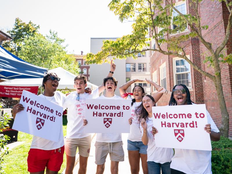 A group of Harvard College students cheer while holding up signs to welcome the incoming class.