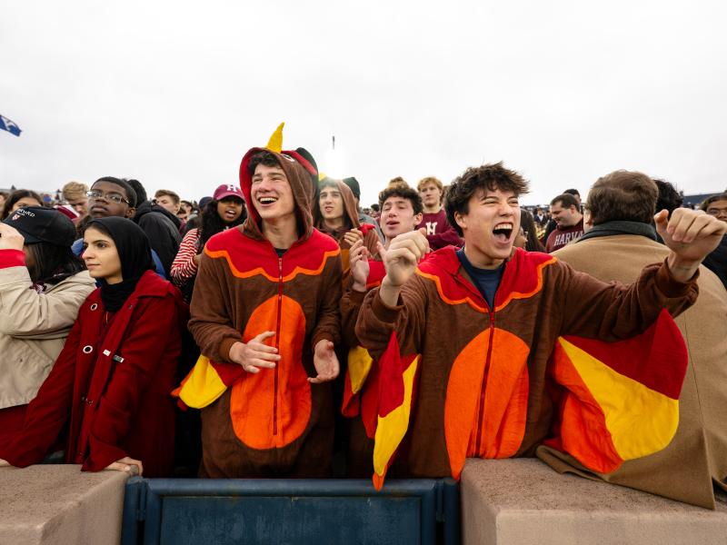 Two young males wearing turkey onesies in the front row of the stands.
