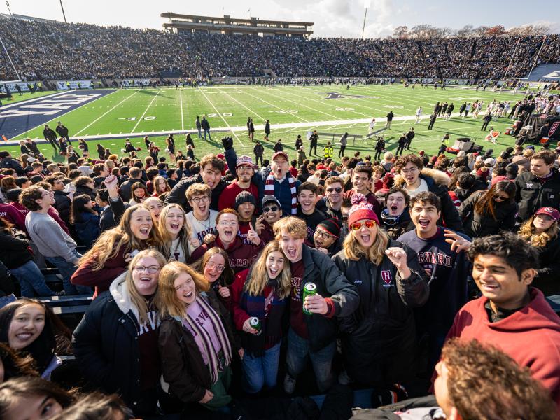 A group of students smile in the crowd with the Dean of Harvard College, David Deming.