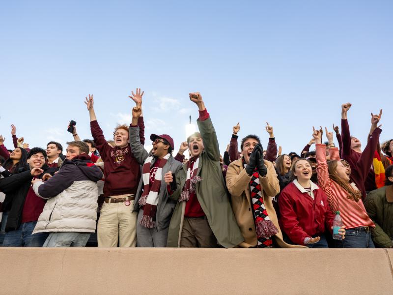 A line of Harvard College students cheer empatically in the front row at the Harvard-Yale game.