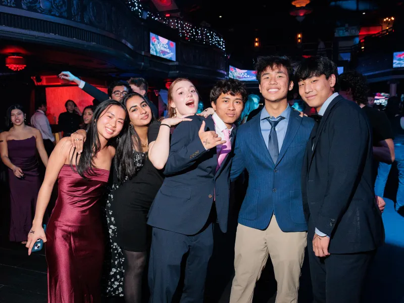 A group of students in formal clothing pose together during the Quad Formal.