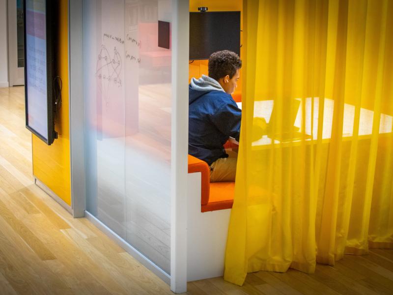 A yellow curtain surrounding a student studying in a private room.