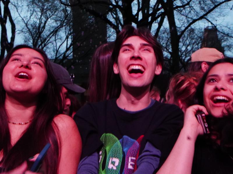 Three students showing excited faces while watching the headlining performer.