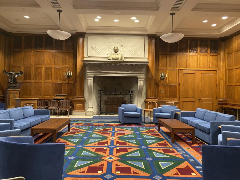 Various blue chairs sitting on top of a colorful carpet in a large room with wooden panels.