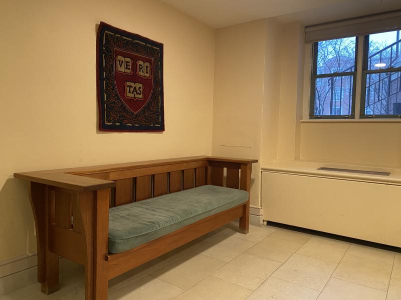 A singular couch sitting underneath a woven Veritas tapestry.