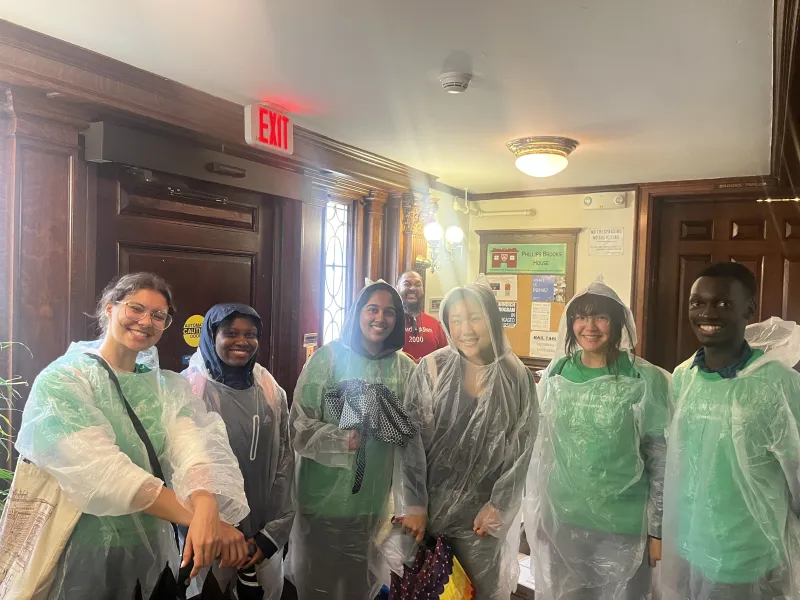 A group of students wearing ponchos to shield them from the rain during outdoor volunteering.