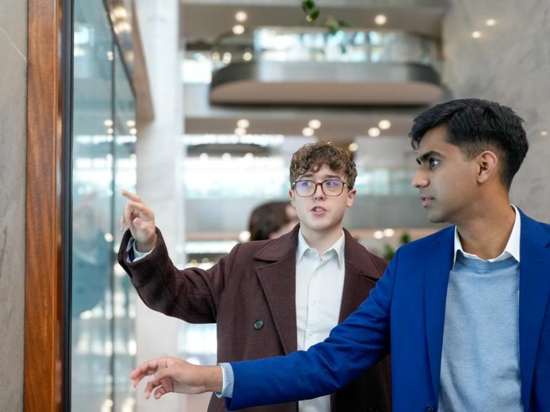 Students pointing at a board to determine where they need to be next during the Wintersession.
