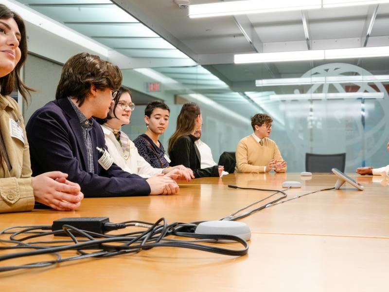Students sitting at a boardroom table before a presentation.