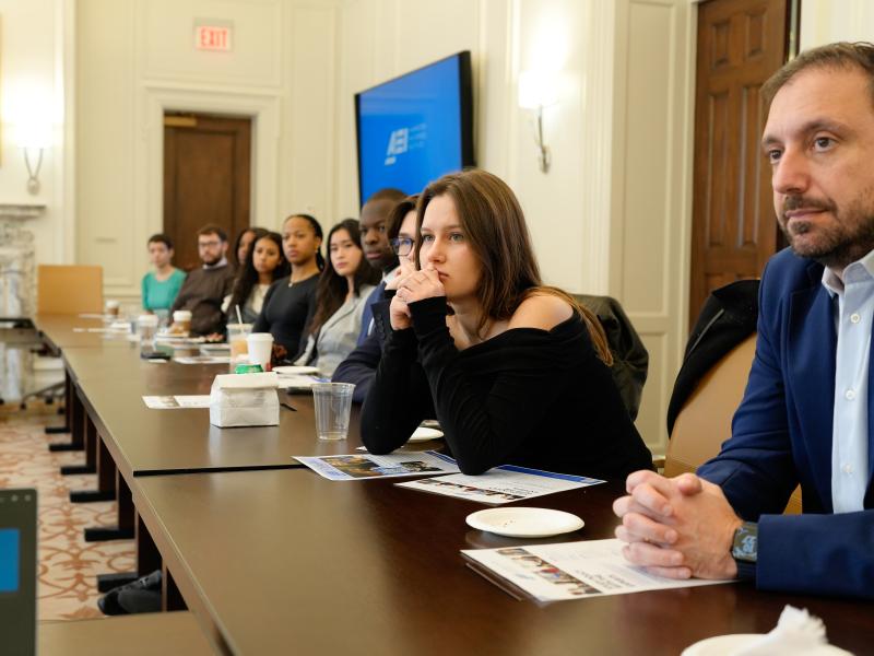Students seated at a table listening intently to the American Enterprise Institute.