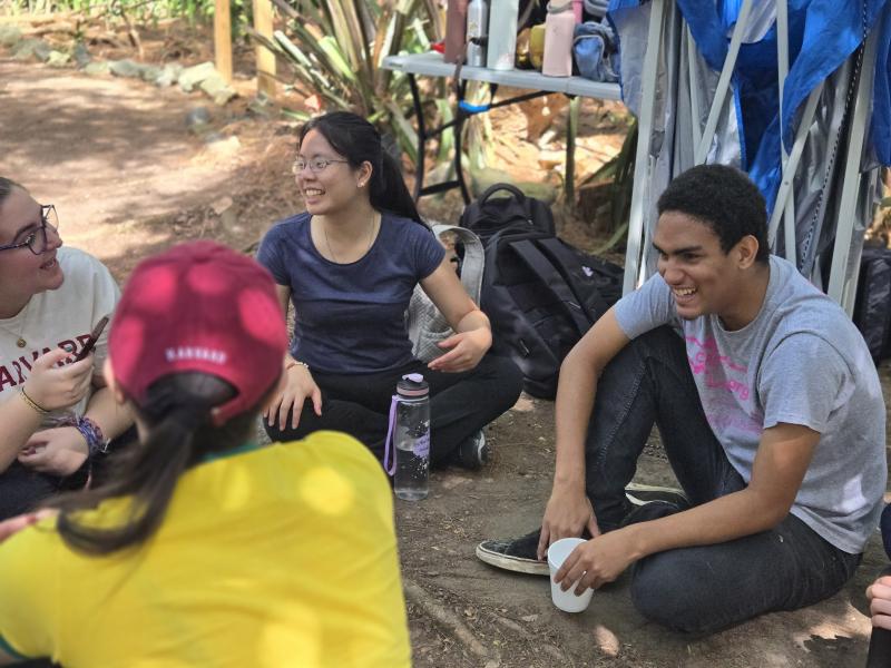 Members of the Catalyst cohort sitting on the outside ground in a circle talking to each other.