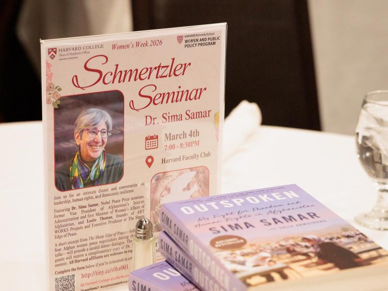 Flyer for the Schmerztler Seminar with Dr. Sima Samar next to a stack of her book “Outspoken” on a table.