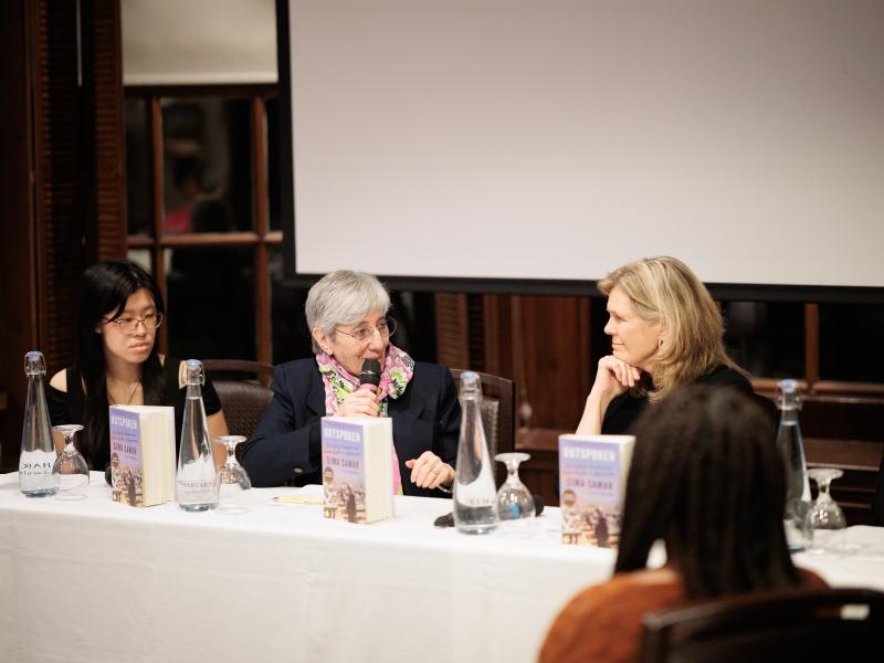 Panel of four women seated at a table with microphones and books, engaged in a discussion.