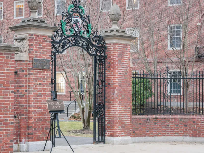 Brick entrance gate to John Winthrop House with a freestanding “Winthrop House” sign beneath ornate ironwork.