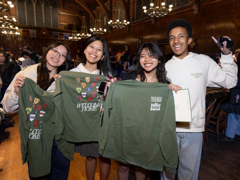 Students holding up green "Housing Day 2026" shirts.