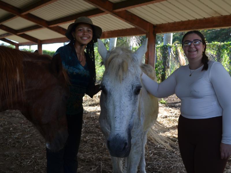 Tiffany Armour ‘29 and Marta Ramos Caimari '29 petting the horses on the equine therapy farm.