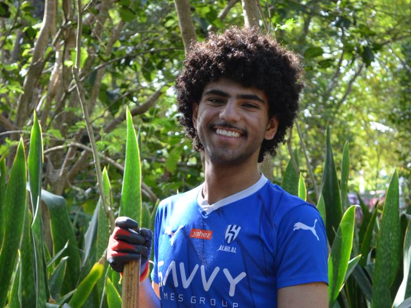 Husam Ramadan ‘29 smiling at the camera while holding a shovel at the coastal forest worksite.