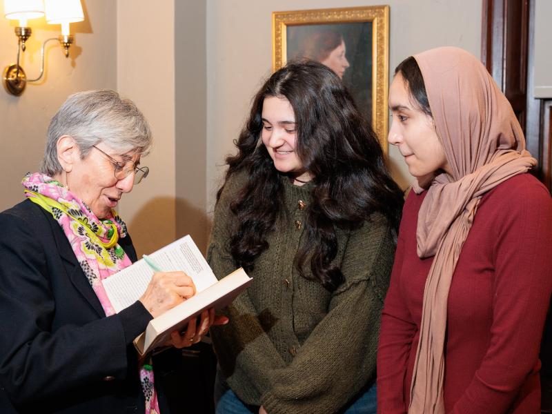Dr. Sima Samar signs a book for two smiling young women after an event.