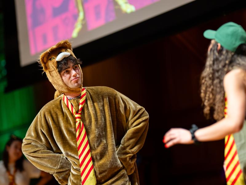 A student performer dressed in a bear costume onstage.