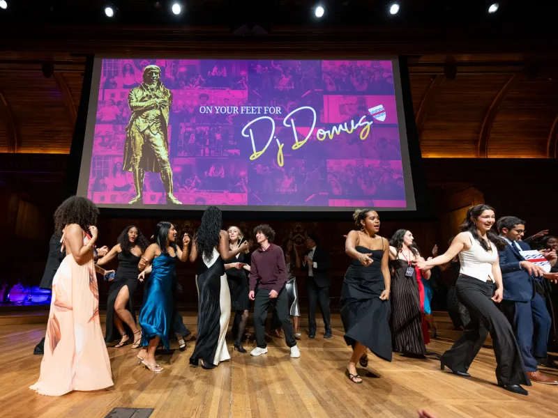 A group of students dancing onstage in their formal attire.