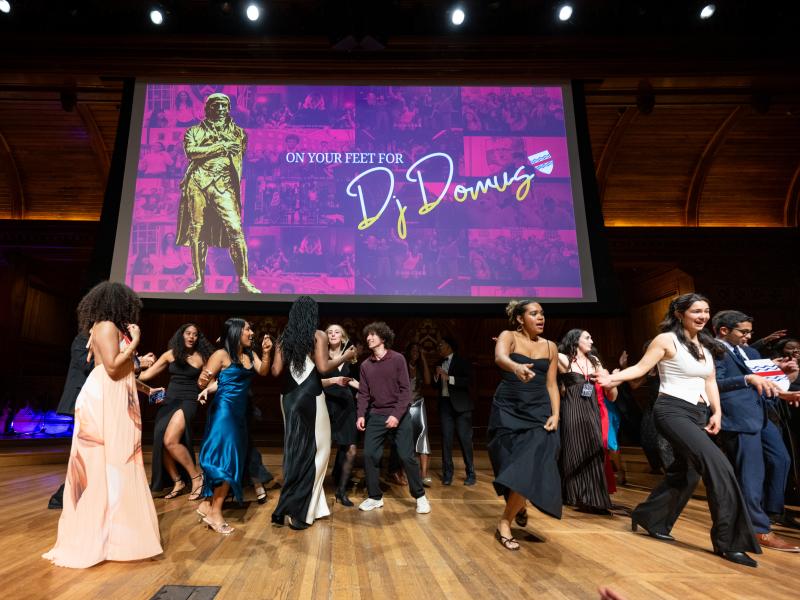 A group of students dancing onstage in their formal attire.