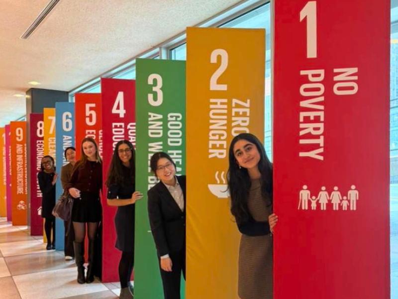  Students peek out from behind colorful UN Sustainable Development Goal pillars, from “No Poverty” to “Industry and Infrastructure.”