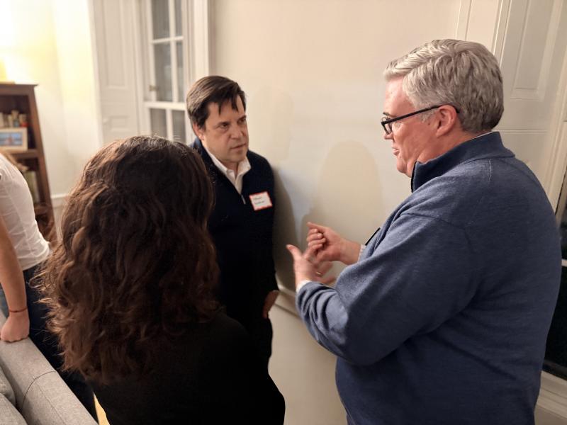 Two adults and a student stand near a wall, engaged in a close conversation.