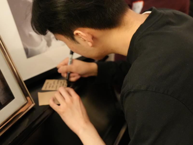 Student leans over writing a note on a small card.