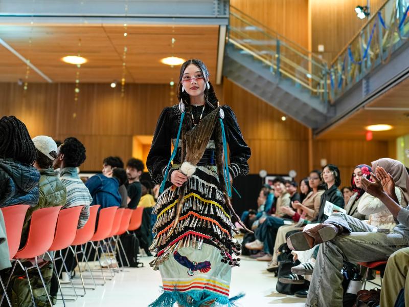 Aaliyah Decker ‘26 walking the runway at the Cultural Rhythms Fashion Show wearing a jingle dress inspired by Indigenous cultures.