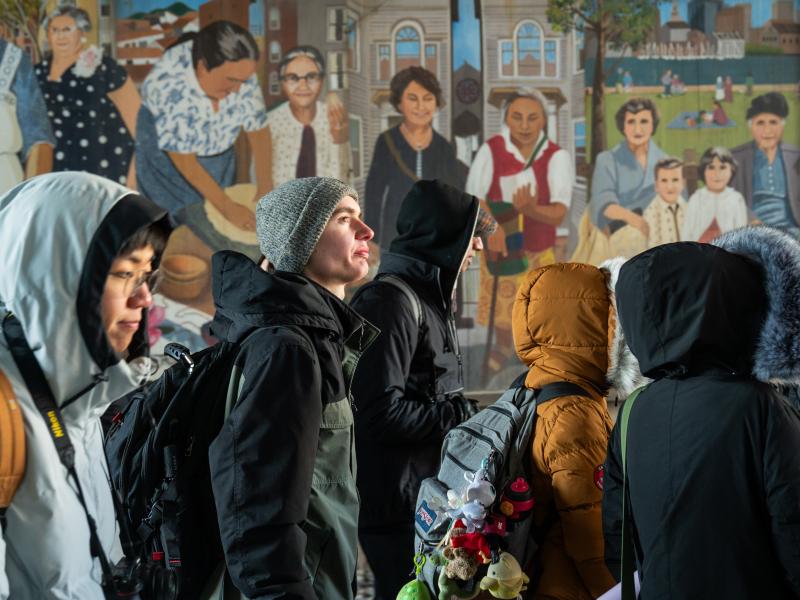 A group of students walking in a tunnel, with one looking upward.