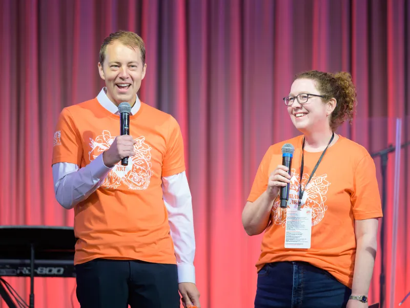 Danoff Dean of Harvard College David Deming (left) and OFA Director Fiona Coffey (right) onstage together in matching orange Arts Fest t-shirts.