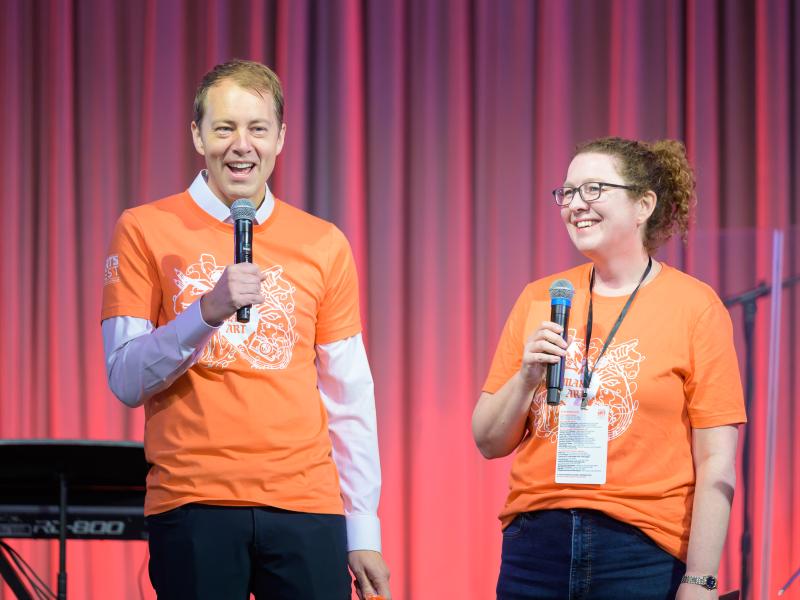 Danoff Dean of Harvard College David Deming (left) and OFA Director Fiona Coffey (right) onstage together in matching orange Arts Fest t-shirts.