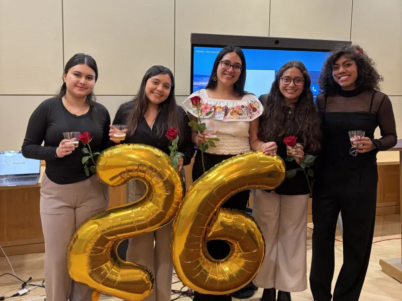 Lizbeth and four friends who just presented at the Latinx Senior Thesis Forum pose for a photo. Each person is holding a red rose.