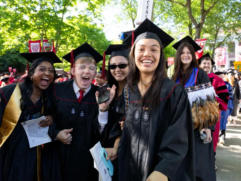 A group of four students wearing regalia looking at the camera and smiling.