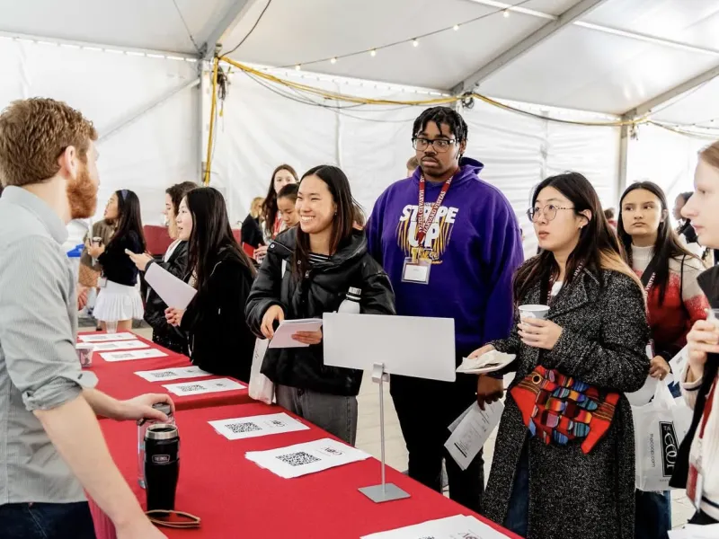 Visitas Concentration Fair 2024. Students lined up at table listening to a concentration advisor.