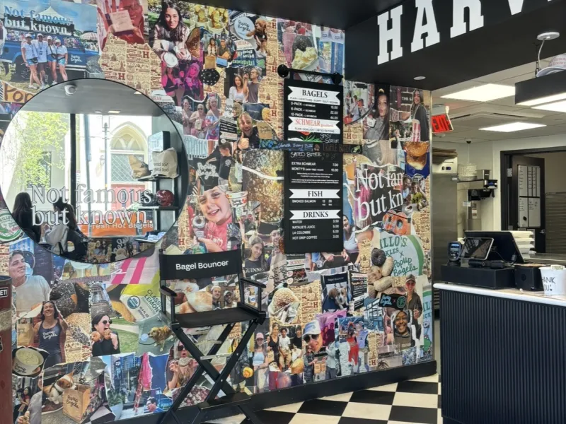 Inside of a bagel shop with a collage of picture, a mirror, and checkered floor tiles