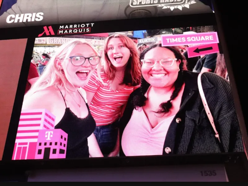 Three friends on a billboard in times square. 