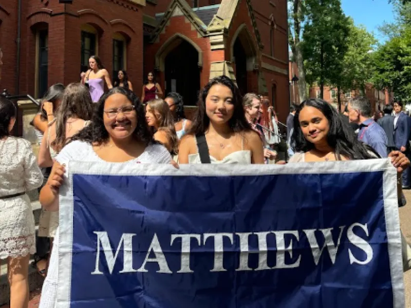 Three roommates holding their first-year dorm flag.