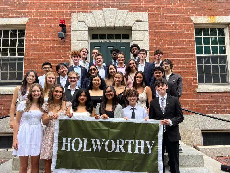 A diverse group of first-year students gather for a group photo in front on their house in formal attire