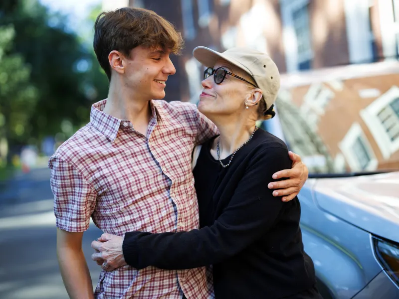 A young male student (left) being hugged by his mother (right) while they looked at each other.