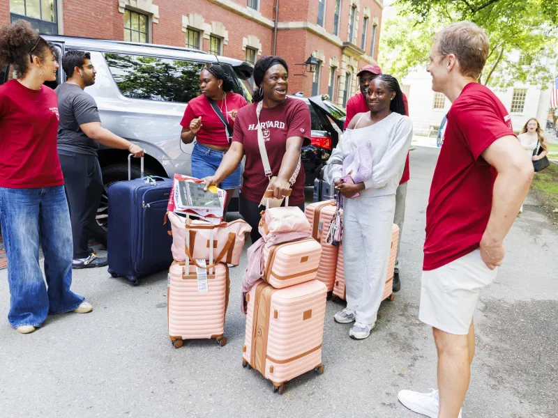 Dean David Deming greeting a family with pink suitcases as they rolled their luggage across the yard.