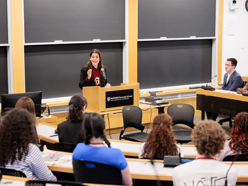 Nathalie Reyes standing in front of the classroom at a podium speaking to the group.