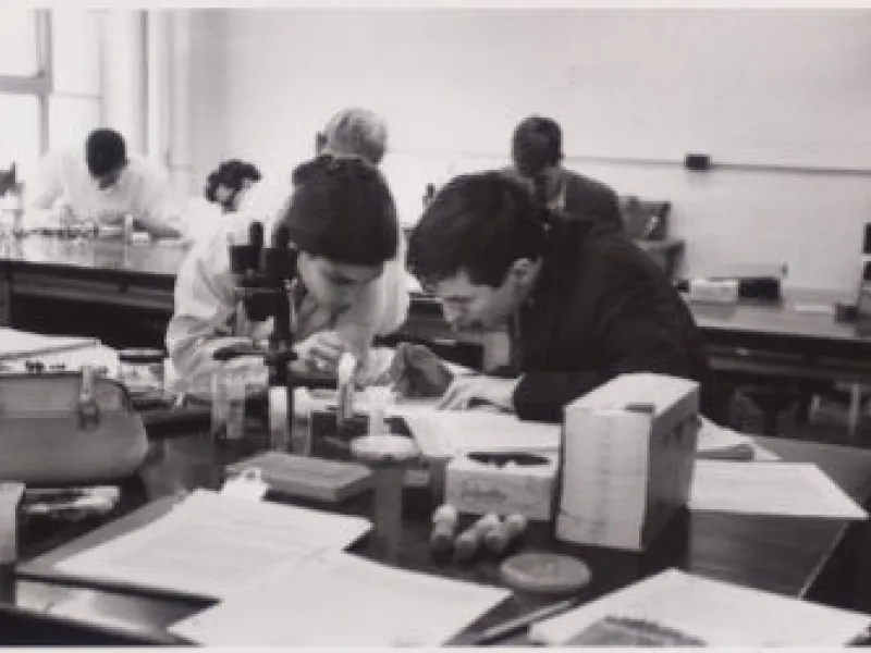 A black and white image of two students hunched over on a lab bench in the mid 1900s.