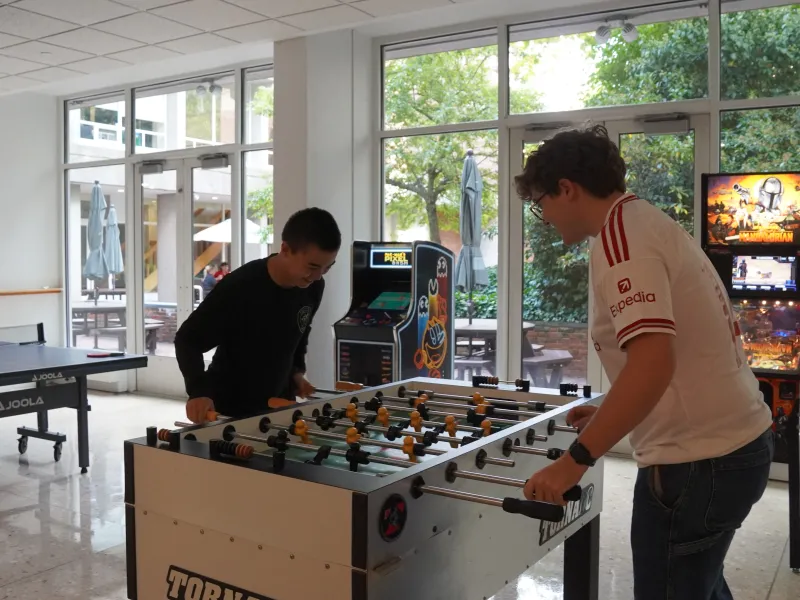 Two male students playing on a fooseball table inside Currier House in 2026.