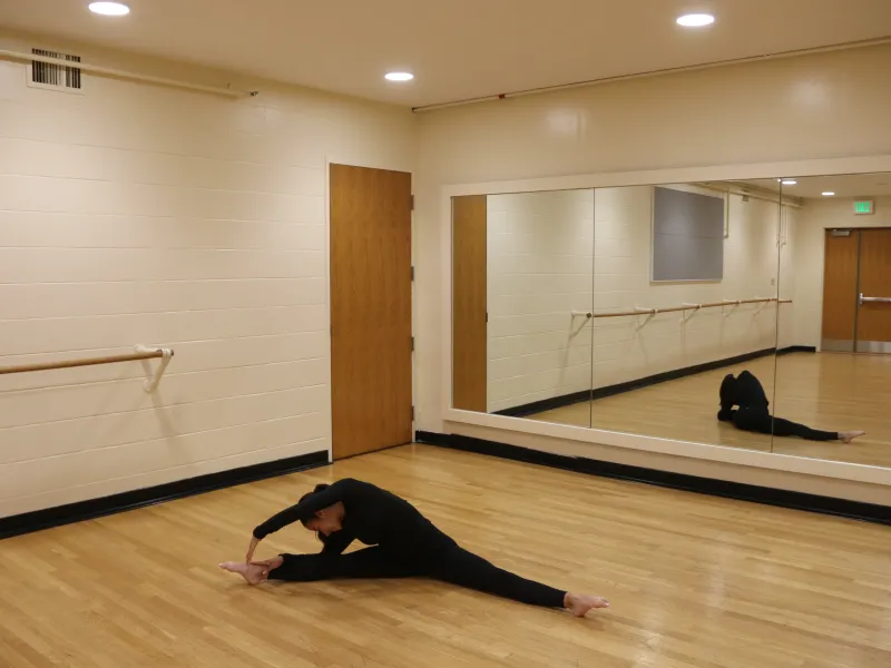 A current student stretching on the floor of Eliot House studio.