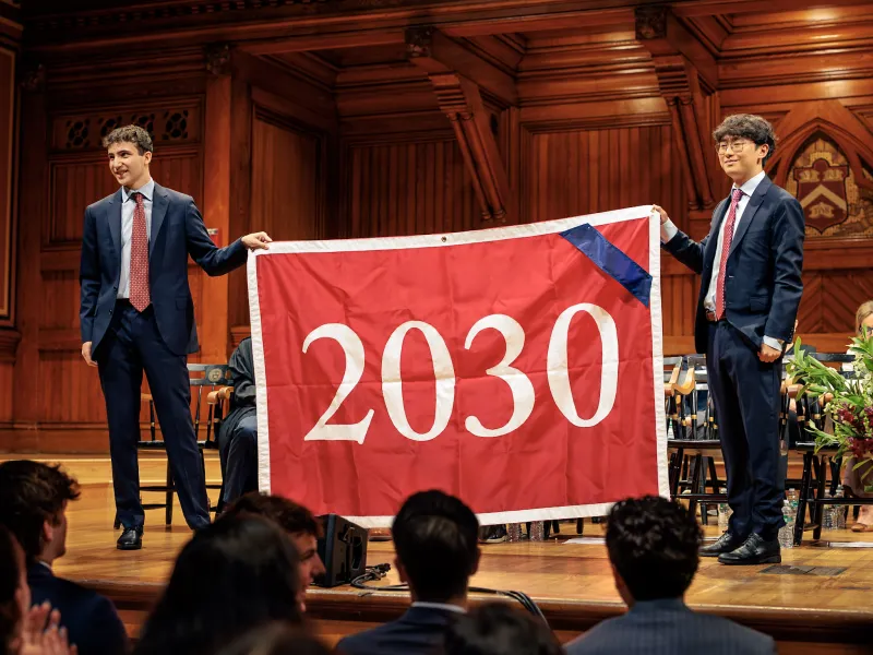 Zach Berg '28 and Daniel Zhao '28 holding up the Class of 2030 banner onstage.