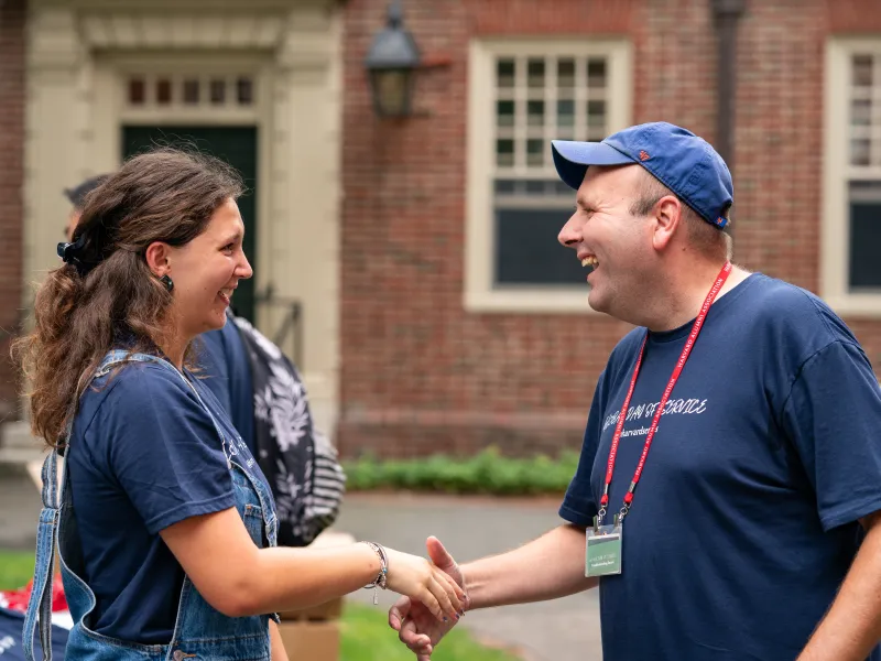 Assistant Dean of Civic Engagement and Service, Travis Lovett, shaking hands with a student volunteer.